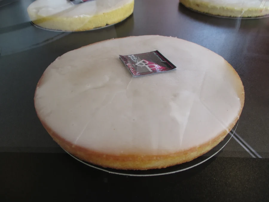 Un gâteau nantais entier recouvert de son glaçage blanc, vu de côté